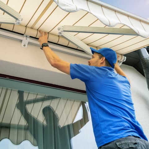 Worker installing a window awning