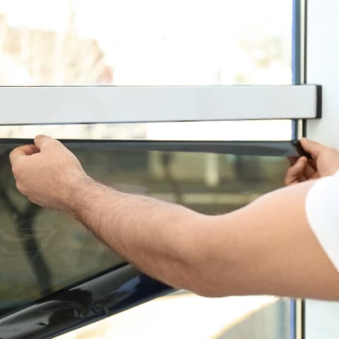 Worker applying a tint to a window